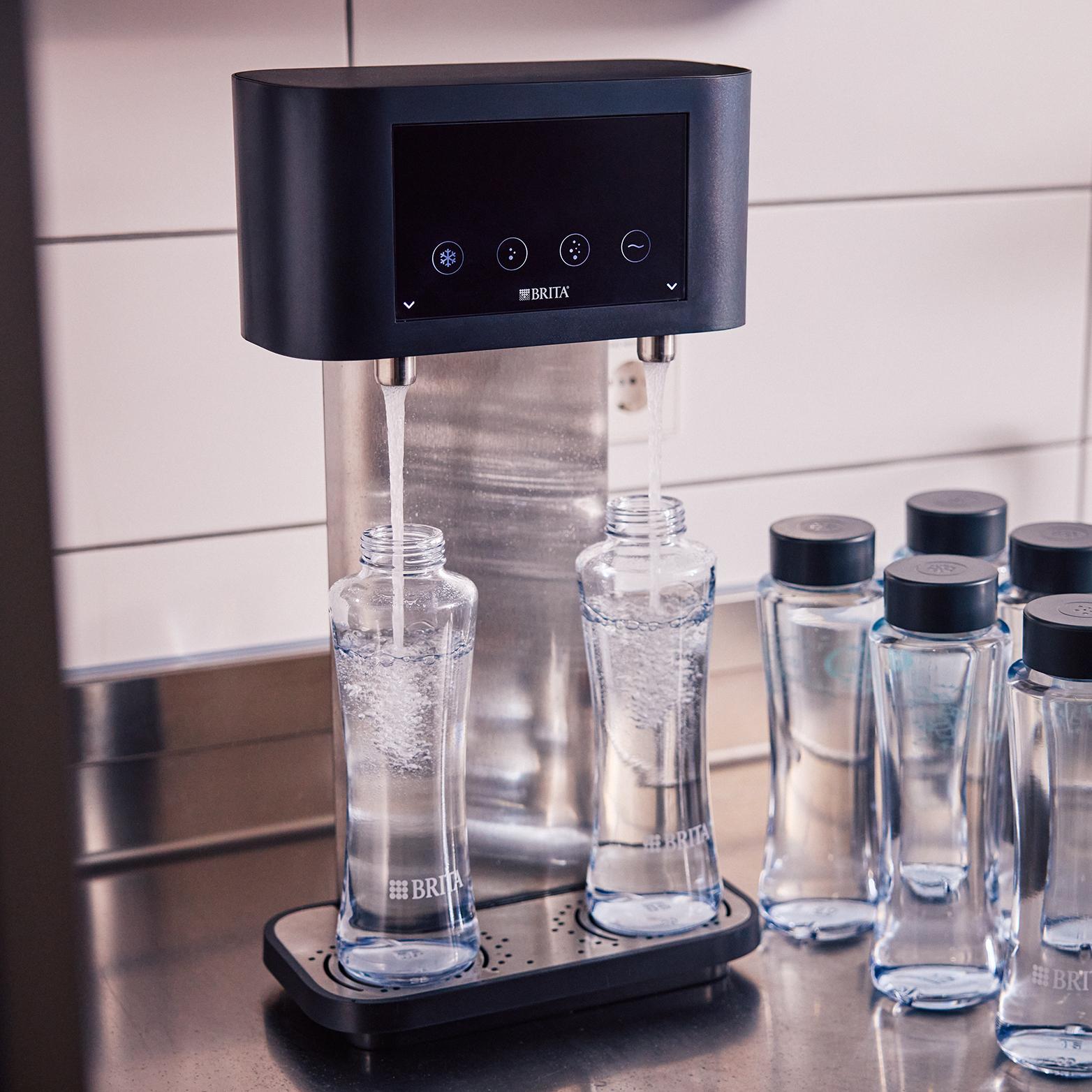 BRITA mains-fed dispenser filling two glass bottles with filtered water in a workplace kitchen